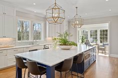 a large kitchen with an island in the middle and chairs at the end, surrounded by white cabinetry