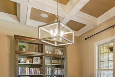 a dining room table and chairs with bookshelves in the center, along with a chandelier hanging from the ceiling