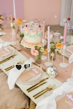 the table is set with pink and gold plates, napkins, and cake on it