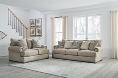 a living room with two couches and a rug in front of the window on the floor