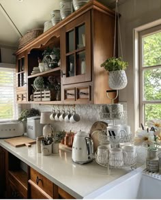 a kitchen with wooden cabinets and white counter tops, filled with pots and pans