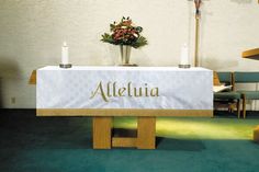 an altar with candles and flowers on it in front of a wall that says, alleluia