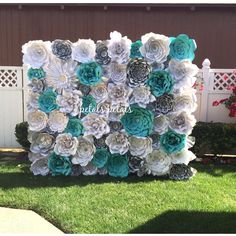 an outdoor backdrop made out of paper flowers and succulents is displayed in the grass