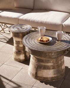 two coffee tables sitting next to each other on top of a stone floored patio