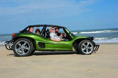 four people in a green car on the beach