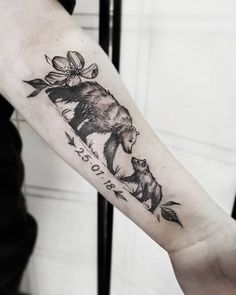 a bear and cub tattoo on the left arm, with flowers around its neck in black ink