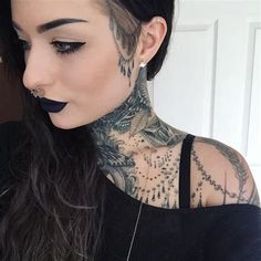 a woman with tattoos and piercings on her face is looking down at the camera