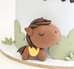 a close up of a cake on a white surface with animals and plants in the background