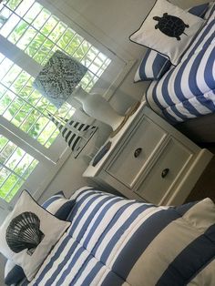 two beds with blue and white bedding in a bedroom next to window covered by shutters