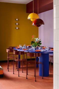 a blue table with orange plates on it in front of a yellow and red wall