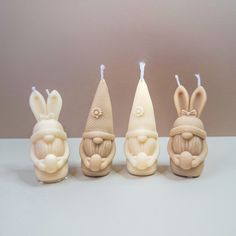 four candles with faces and ears are lined up in the shape of santa claus's hats