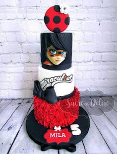 a three tiered cake with ladybug and red ruffles on top