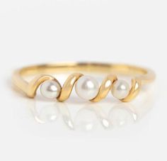 a gold ring with three pearls on it