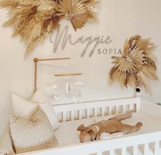 a baby's room decorated in white and gold with large pamolite leaves on the wall