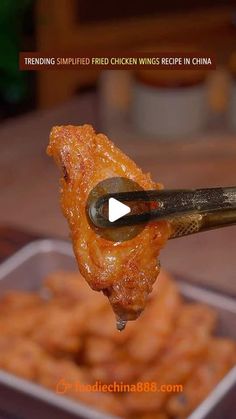 a spoon full of fried chicken wings being held by a person with tongs over them