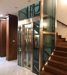 an elevator with glass doors and wooden steps in a large room that has marble flooring