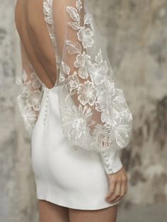 the back of a woman's white dress with sheer sleeves and flowers on it