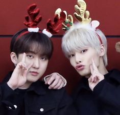 two young men wearing reindeer antlers on their head and pointing fingers at the camera