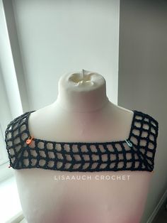 a mannequin wearing a black crochet top with an orange bead on it