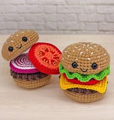 two crocheted hamburgers sitting on top of a table next to each other