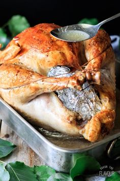 a roasted turkey in a roasting pan with a spoon