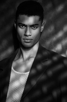 a black and white photo of a young man in a suit looking at the camera