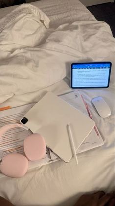 a laptop computer sitting on top of a white bed