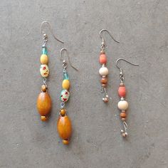 three pairs of earrings with wooden beads and metal hooks on concrete surface, top view