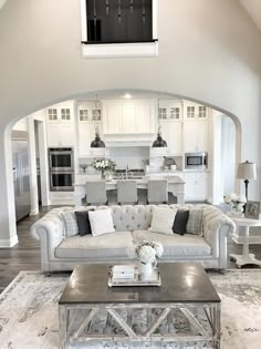 a living room filled with furniture next to a kitchen