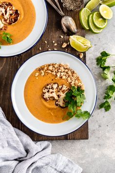 two white plates topped with soup and garnished with cilantro