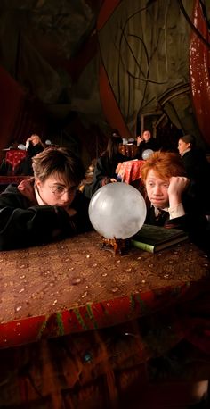 two people laying down on a table with a balloon in front of them and one person looking at the camera