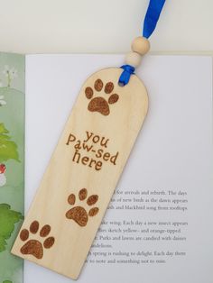 a wooden bookmark with a paw print on it and a blue ribbon around the neck