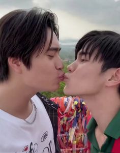 two young men kissing each other while standing next to each other