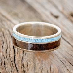 a wedding band with blue and brown wood inlays sits on a wooden surface