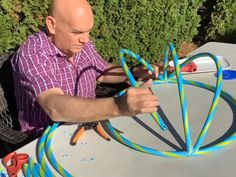 a man sitting at a table working on some kind of thing that is in the air