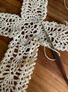 a crocheted cross on a wooden table with scissors