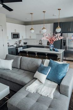 a living room filled with furniture and a kitchen in the back ground, next to an island