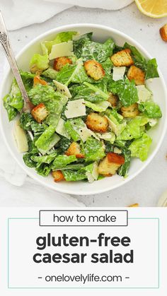 a white bowl filled with lettuce and croutons next to lemon wedges