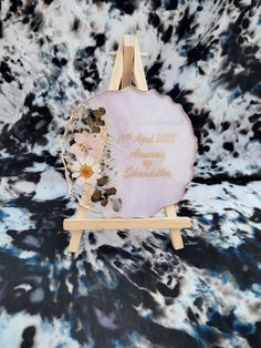 a small easel with flowers on it in front of a black and white background