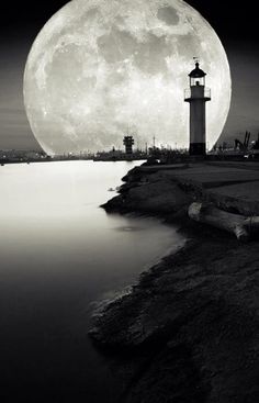 a black and white photo with the moon in the sky above it is an image of a lighthouse