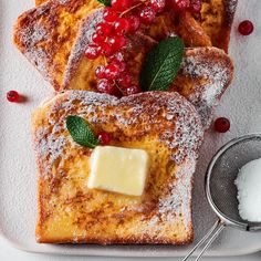 french toast with powdered sugar and fresh berries on the side, topped with butter