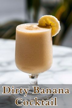 a drink in a glass with a slice of banana on the rim and text that reads dirty banana cocktail