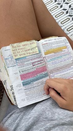 a person is reading a book with sticky notes on the pages and writing in it