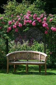 a wooden bench sitting in the middle of a lush green field next to pink flowers