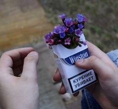 a person holding a tube with purple flowers in it and a sticker on the end