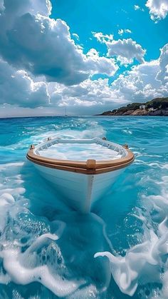 a boat floating on top of a body of water under a blue sky with clouds