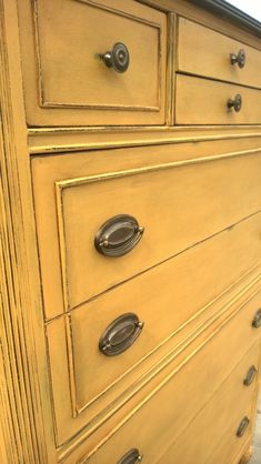 an old yellow dresser with metal handles and knobs