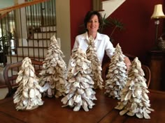 a woman is sitting at a table with some fake trees made out of book pages