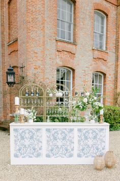 a white and blue wedding reception table with flowers on it in front of a brick building