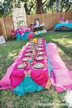 a party table set up with pink and blue cloths, plates and napkins